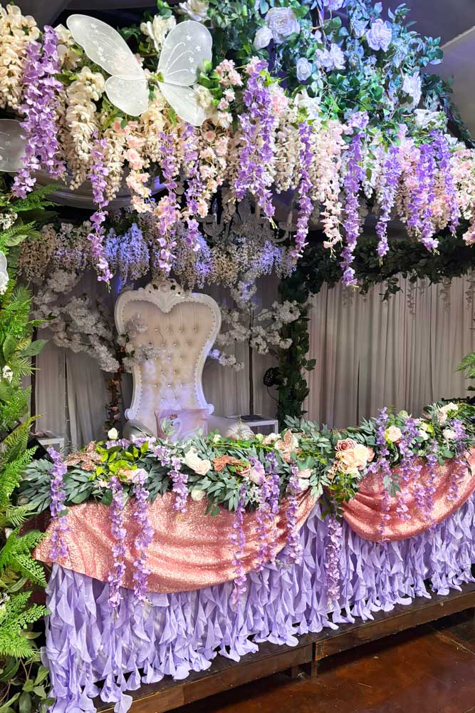 Qinceanera girl on white throne chair with paper fd flowers on top.