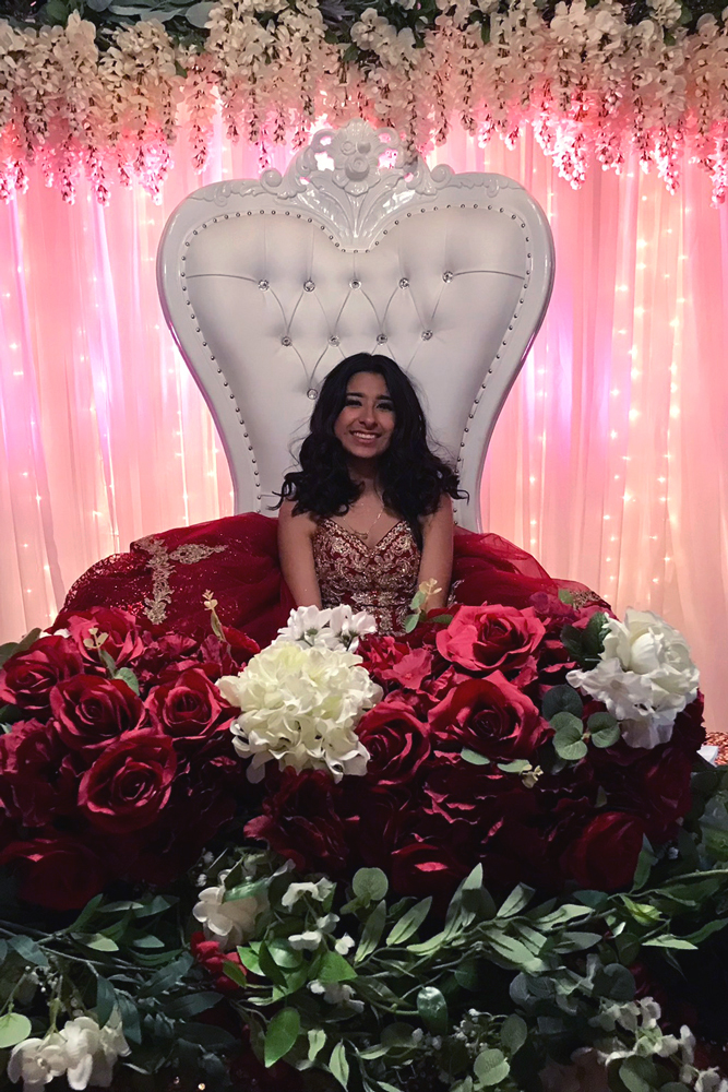Party guests strike a fun pose and taking pictures in front of the greenery wall photo area.