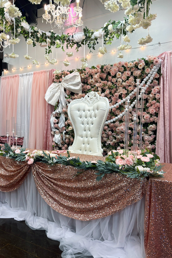 Throne chair in front of floral background with decorated table of honor.