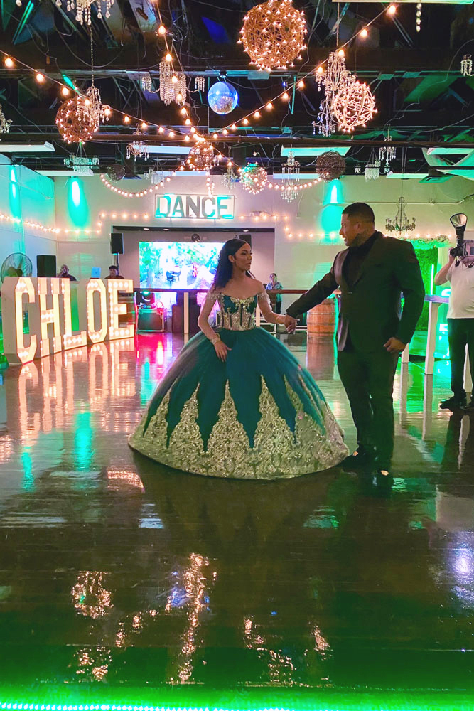 On an illuminated dance floor the quinceaanera girl dances with father