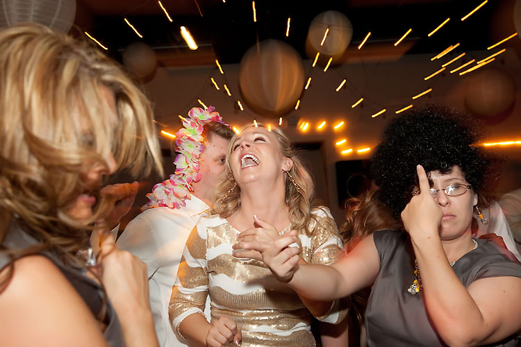Bride and guests on illuminated dance floor after wedding ceremony.