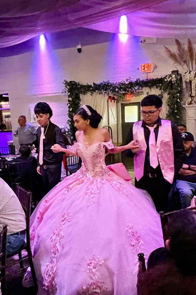 Quinceañera girl with chambalone entering the main ballroom in beautiful dress.