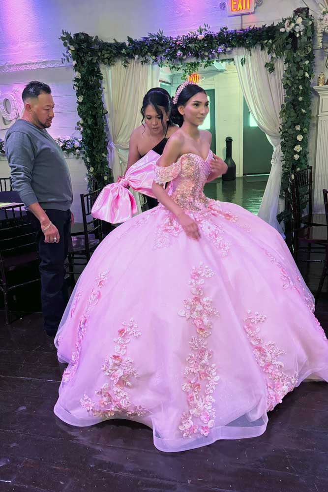Quinceañera girl with mother adjusting the back of her dress preparing for a her beautiful event.