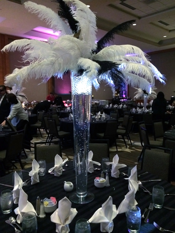 Modern glass pilsner centerpiece with ostrich feathers and lighting accents for an elegant event table at The Chateau at Forest Park