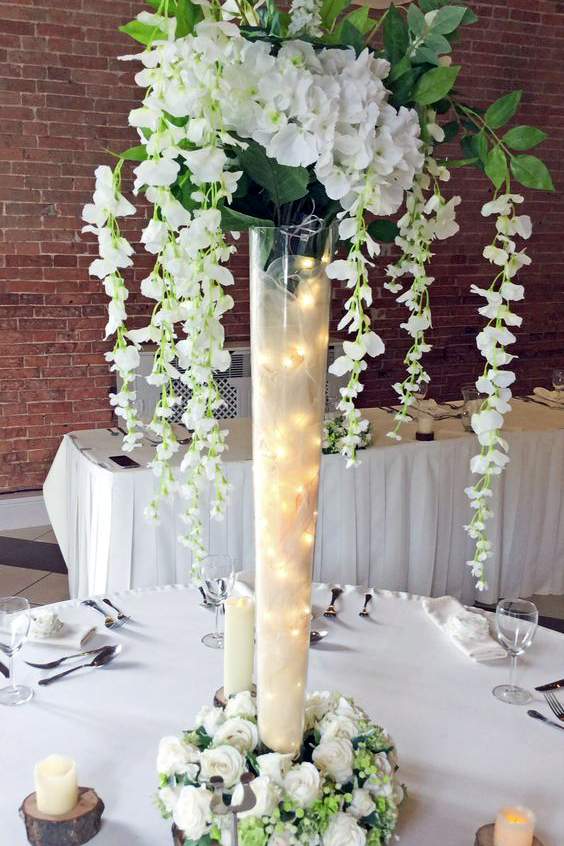 Modern glass pilsner centerpiece with florals, greenery, and lighting acc238ents for an elegant event table at The Chateau at Forest Park