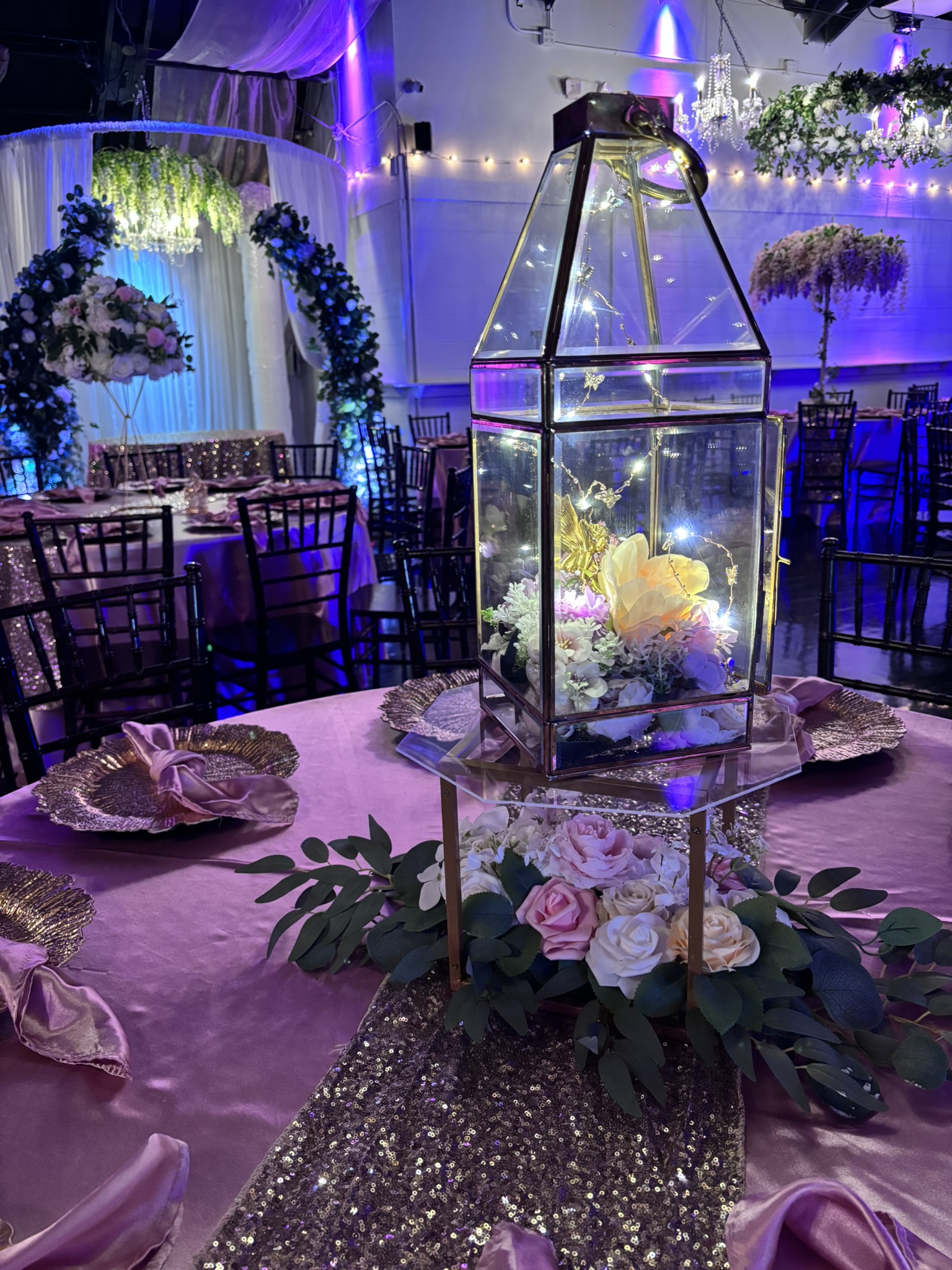 Gold lantern centerpiece with flowers and greenery at The Chateau at Forest Park