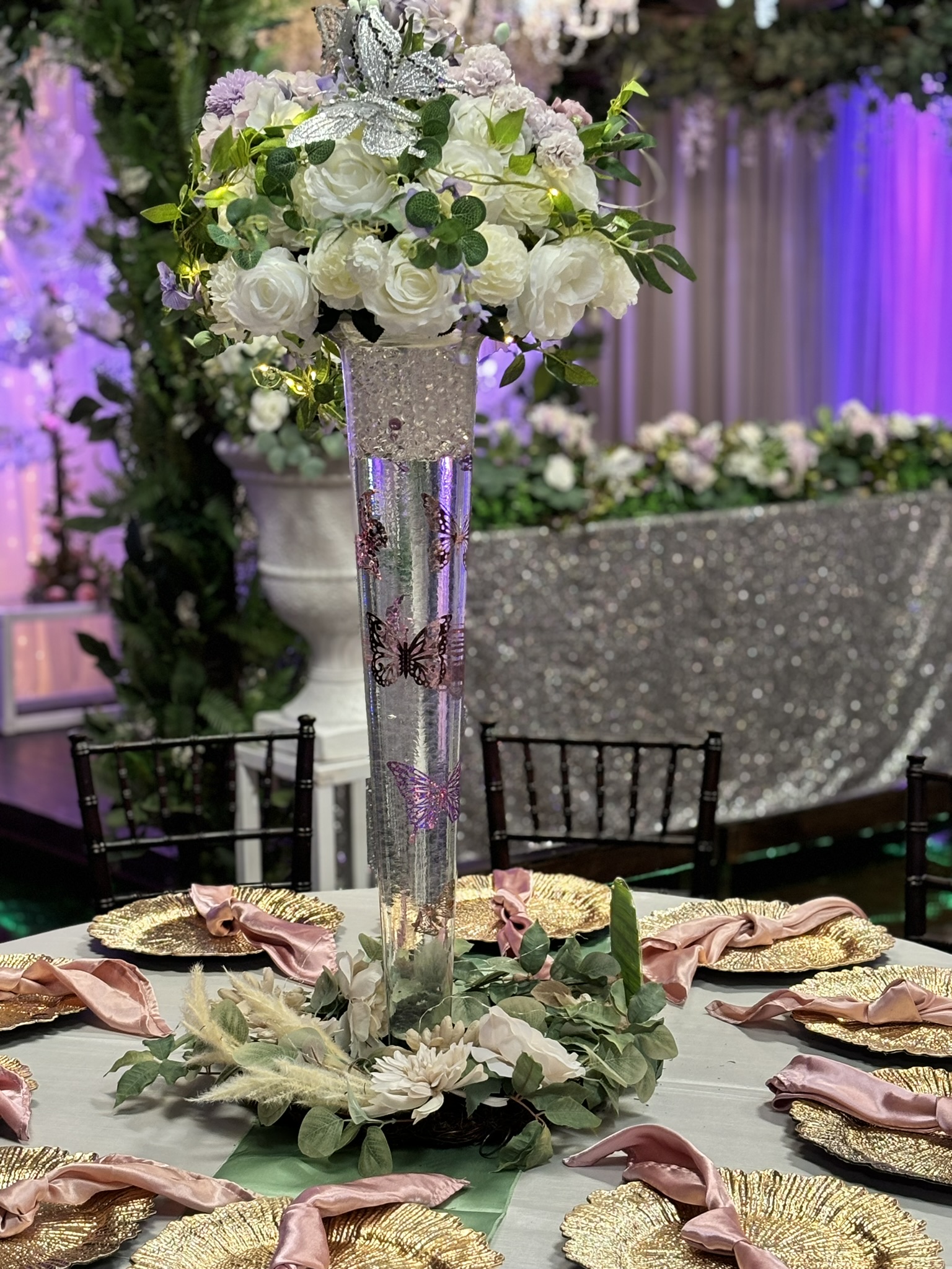 Modern glass trumpet centerpiece with florals, greenery, and lighting accents for an elegant event table at The Chateau at Forest Park