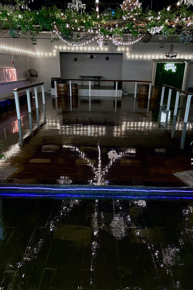 Spacious dance floor and bar area under chandeliers at a corporate event venue
