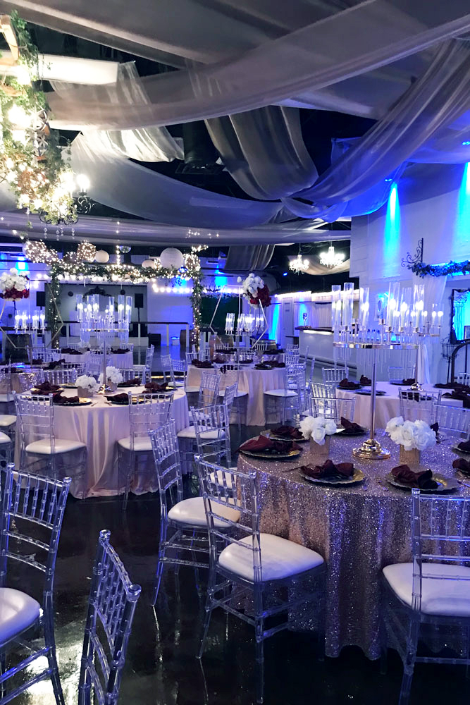 Blue-lit ballroom during event planning walkthrough with ceiling draping and uplighting at a Fort Worth event venue
