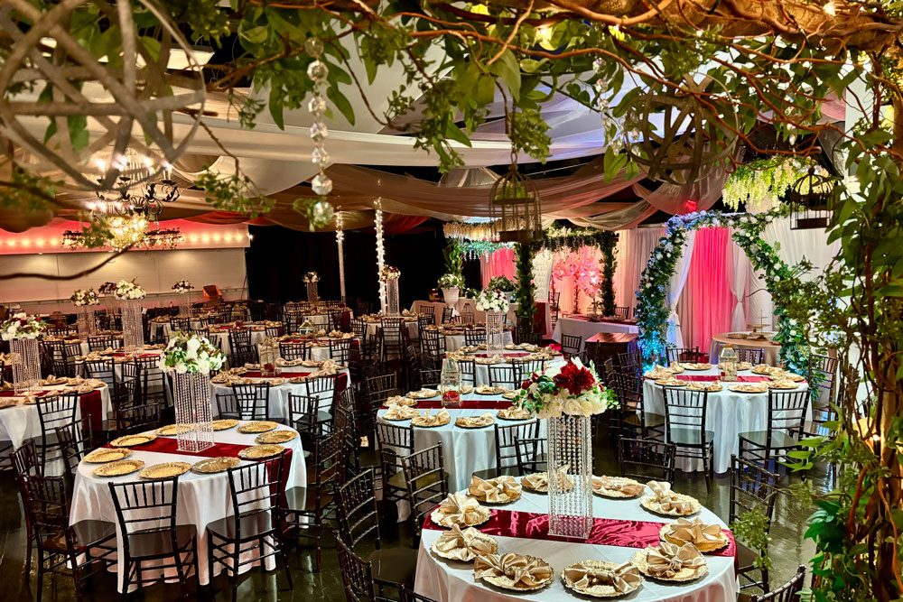 Large-capacity ballroom arranged for a 300-guest reception with draped ceilings and uplighting