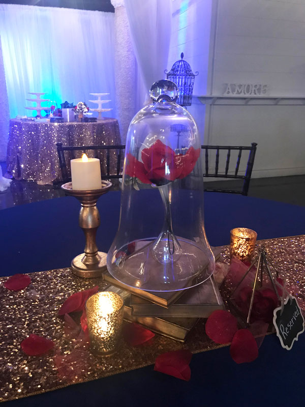 Close-up of romantic candlelit centerpiece with red roses and gold accents