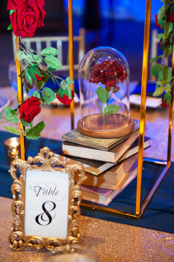 Storybook-style table decor with books, rose centerpiece and warm ambient lighting