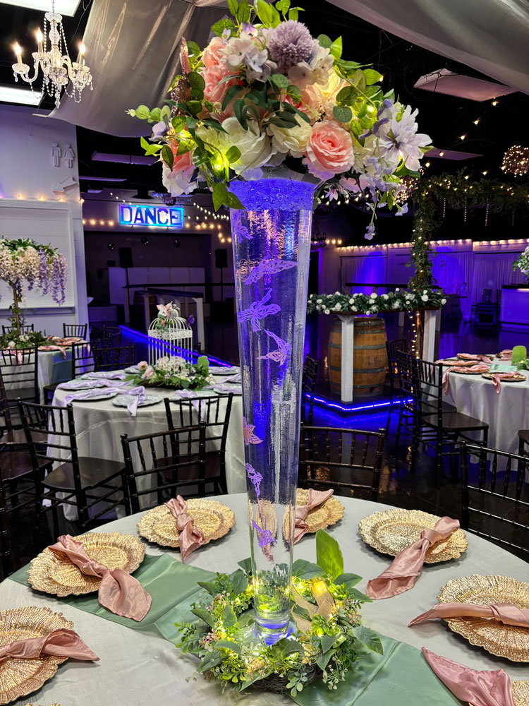 Whimsical glass centerpiece design with butterfly elements, floral accents, and accent lighting