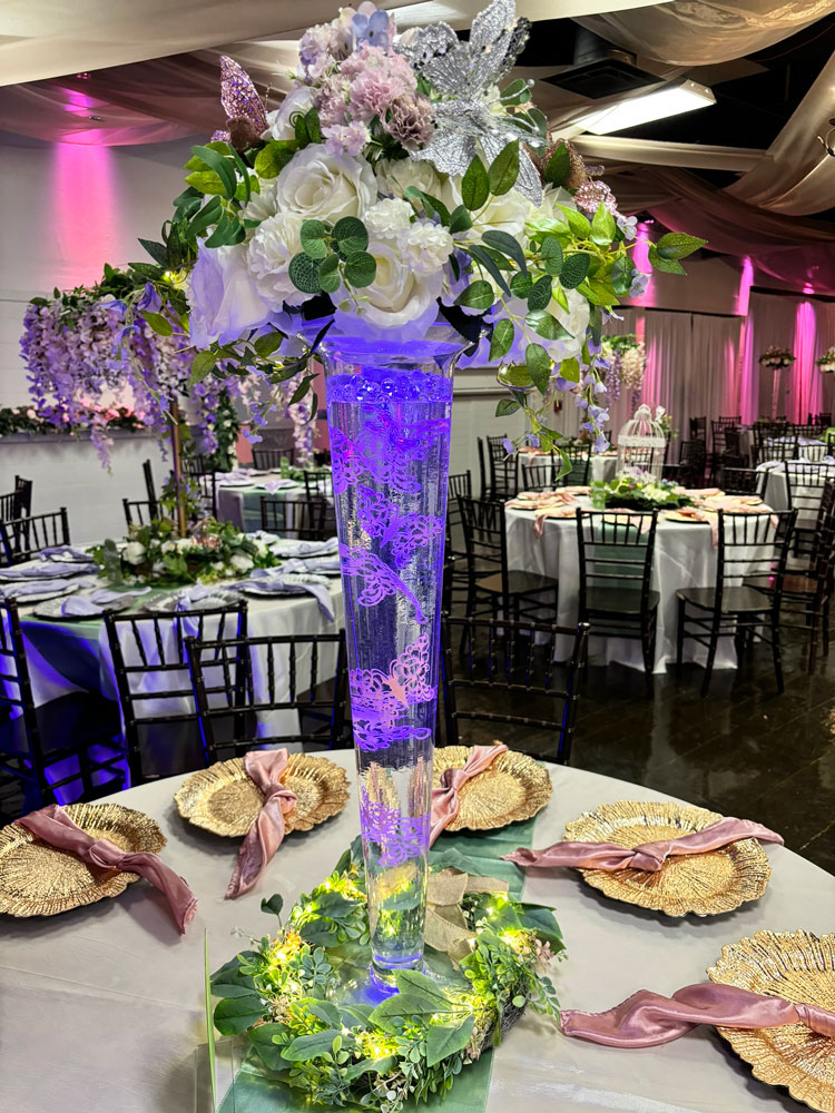 Whimsical glass centerpiece design with floating butterfly elements, floral accents, and accent lighting