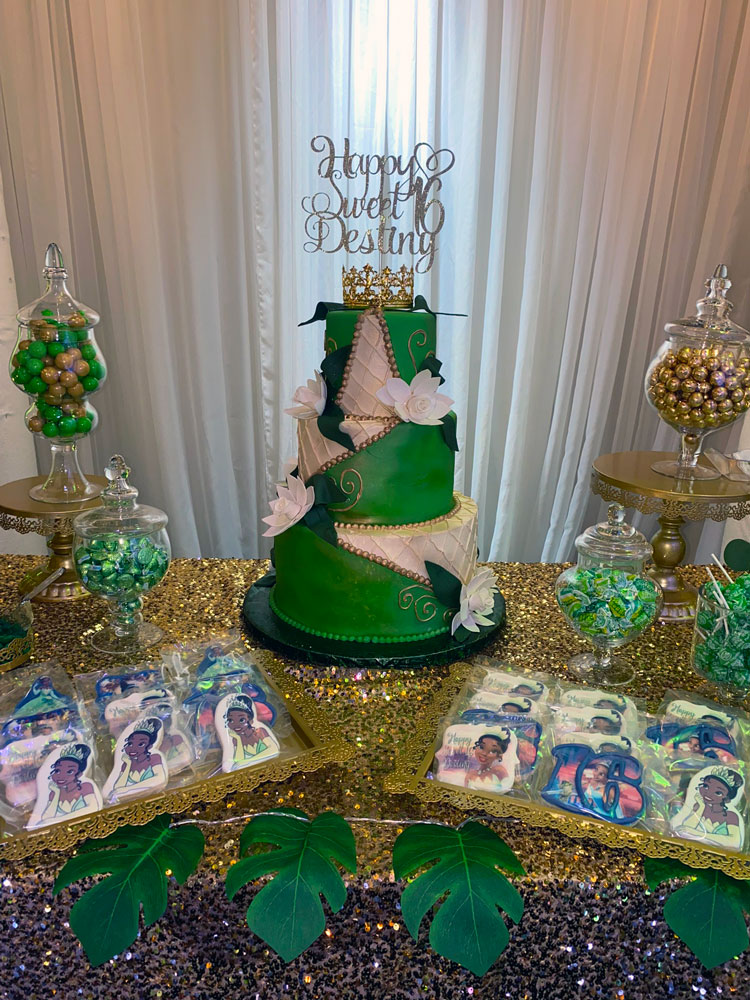 Cake table styled in enchanted forest shades with greenery, candles, and natural textures