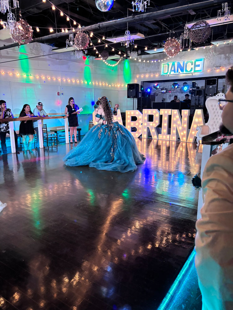 Quince girl on dance floor framed by emerald green uplighting