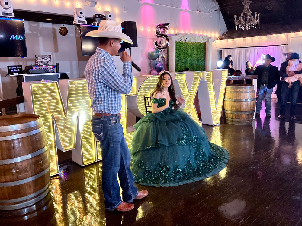 Quinceanera speech on dance floor surrounded by green lighting