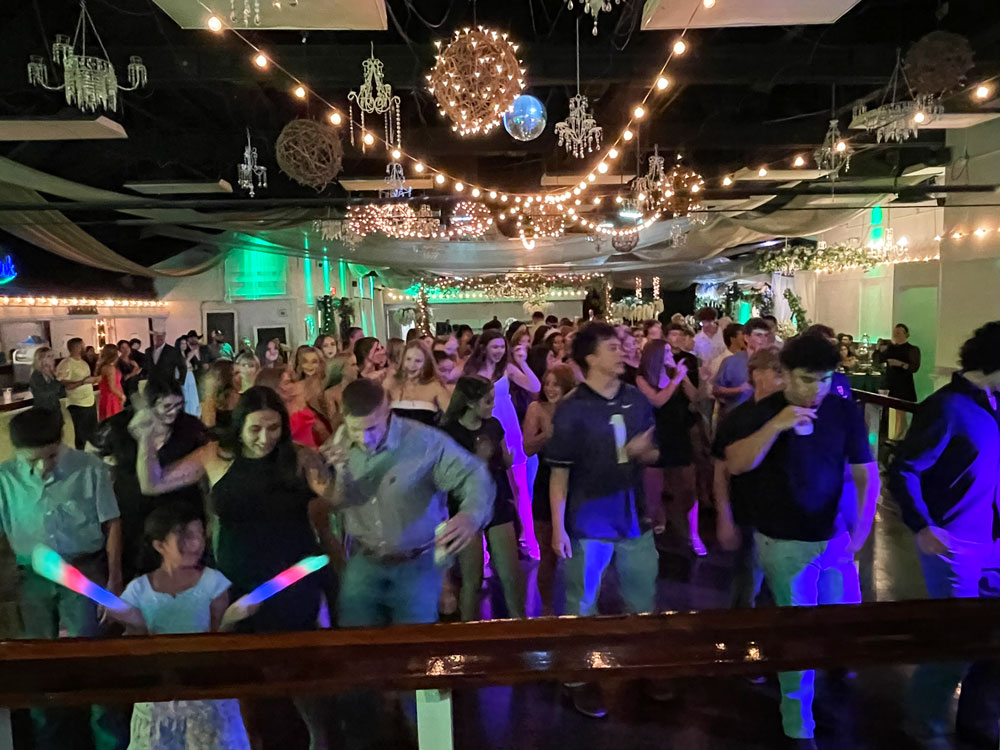 Purple uplighting surrounding dancers on a polished dance floor for a romantic celebration
