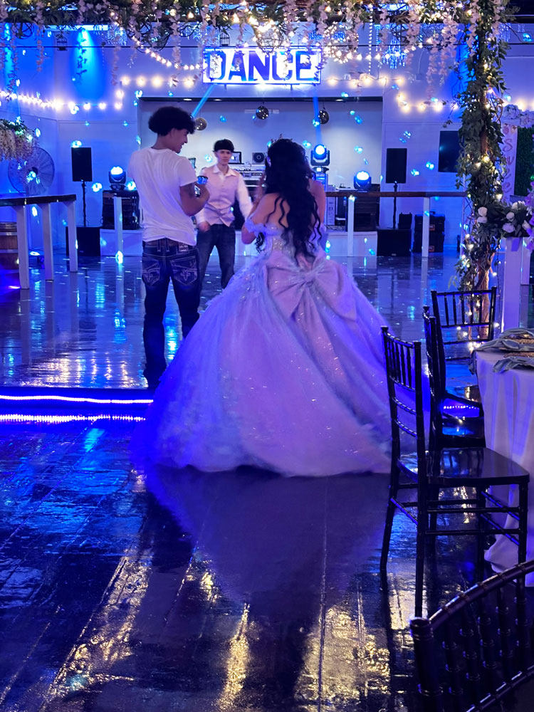 Quine girl on ballroom dance floor accented with vibrant lighting and dramatic ambiance