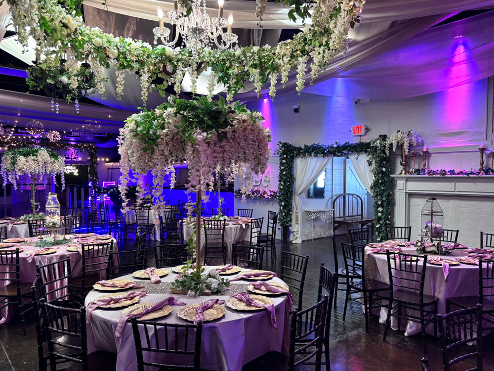 Elegant ballroom styled in shades of purple with soft uplighting and formal place settings