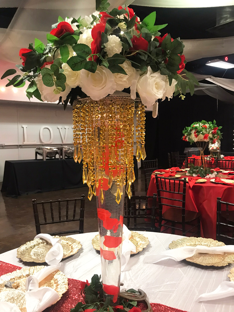 Guest table with tall jeweled  floral centerpiece styled in layered shades of red